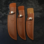 Étuis en cuir marron Punisher pour couteaux – protection robuste, couture renforcée, tailles S/M/L – fond pierre sombre.