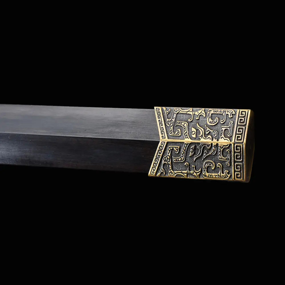Gros plan sur l’embout du fourreau en ébène de l’épée chinoise Jian HAN YUN, avec garniture métallique dorée gravée, bois sombre poli et fond noir.