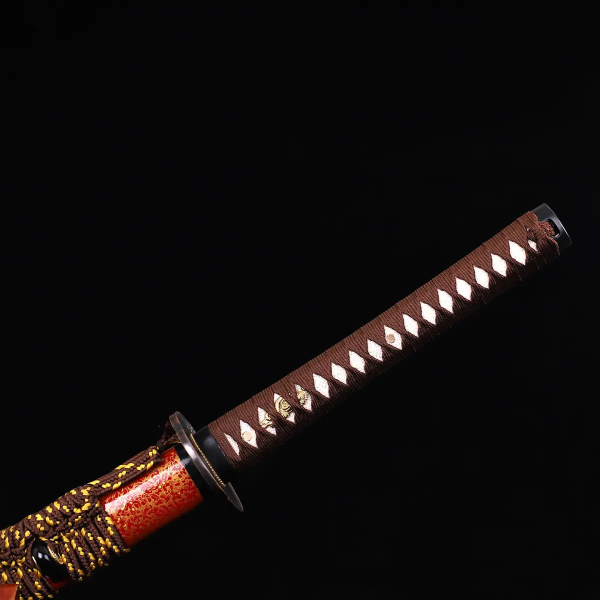 Détail du katana japonais Kannon Ryū montrant la poignée tsuka en tressage marron sur samegawa blanche, finition artisanale avec ornements dorés, sur fond noir studio Blade Bushido.