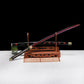 Katana japonais Shusui en acier carbone 1045 avec lame noire et rouge, présenté sur un support en bois traditionnel.