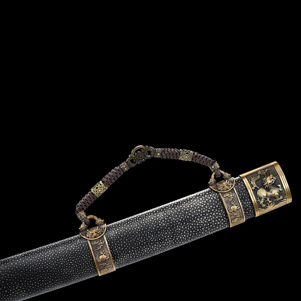 Gros plan sur le fourreau du sabre chinois Dao BAI LONG sur fond noir, avec revêtement sombre texturé, chaîne décorative tressée, anneaux métalliques et garnitures en laiton ornées de motifs dragon.