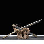 Sabre chinois Dao BAI LONG présenté lame sortie sur un support en bois naturel, avec fond noir, lame sombre à gravures dorées, poignée blanche texturée, garde en laiton et fourreau noir décoré de garnitures dragon.