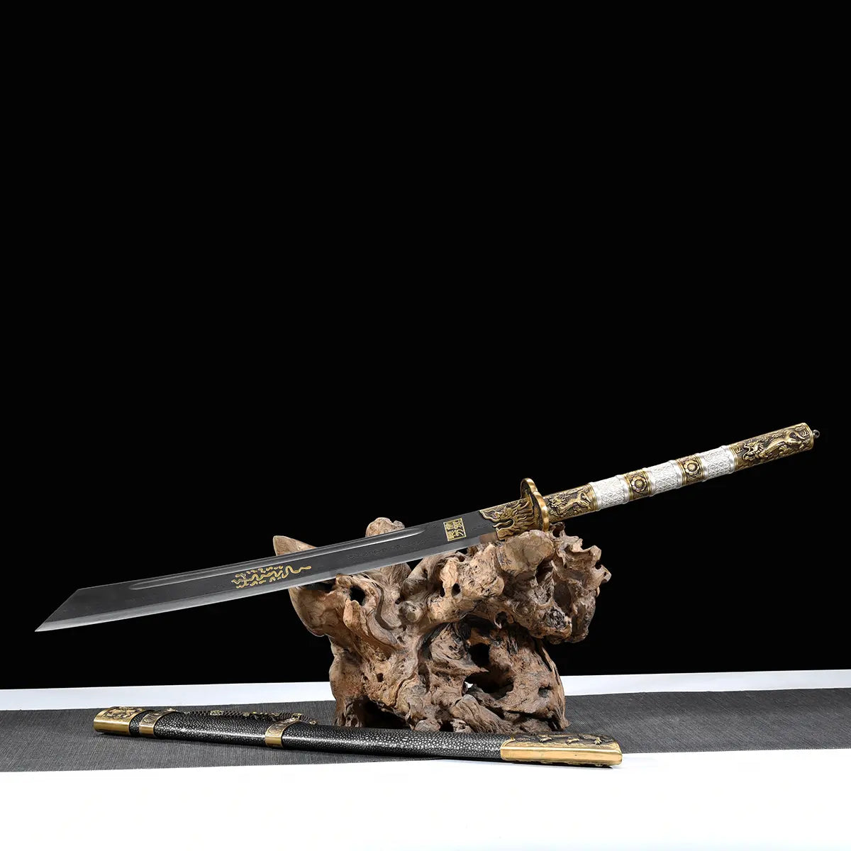 Sabre chinois Dao BAI LONG présenté lame sortie sur un support en bois naturel, avec fond noir, lame sombre à gravures dorées, poignée blanche texturée, garde en laiton et fourreau noir posé à l’avant avec garnitures métalliques.
