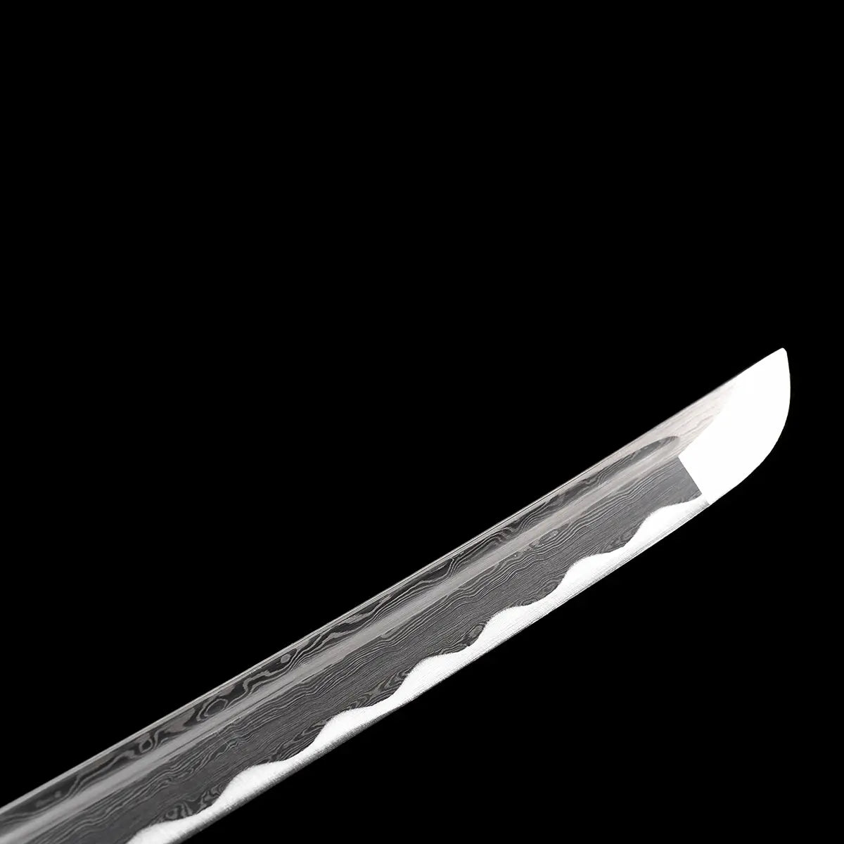 Close-up view of the kissaki of the handcrafted Japanese katana Dokuryu on a deep black background, highlighting the curved blade tip with a sharp polished edge, visible wavy hamon line running along the folded steel, layered grain patterns clearly defined, no scabbard present, minimalist studio composition focused on blade geometry and steel texture.
