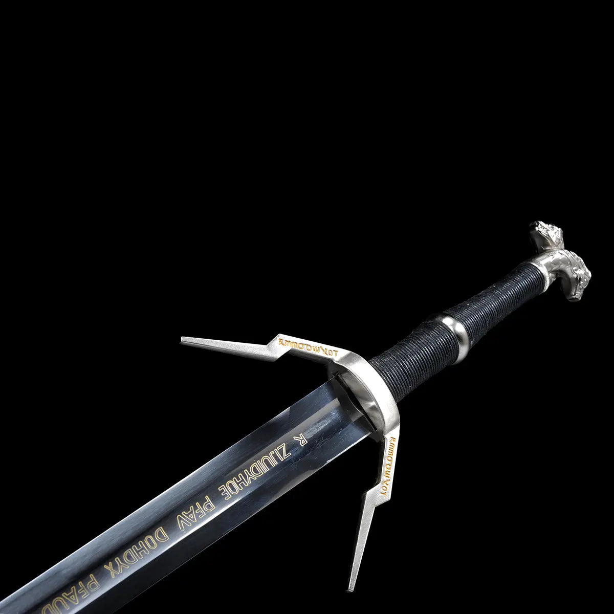 Vue en angle de la garde et de la lame de l’épée longue Geralt de Riv The Witcher 3 sur fond noir uniforme, lame droite en acier poli avec inscriptions décoratives dorées visibles sur le plat, garde en croix anguleuse en métal argenté avec quillons asymétriques gravés, poignée longue gainée de cuir noir texturé et pommeau métallique sculpté partiellement visible, composition mettant en valeur les lignes de l’épée pour cosplay, collection et observation AMHE ou HEMA décorative
