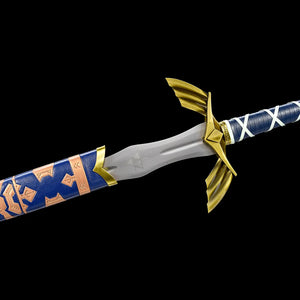 detail de l epee longue Master Sword Legende d Hyrule photographie sur fond noir, gros plan sur la base de la lame en acier carbone partiellement engagee dans le fourreau bleu laque, motifs dores visibles sur le fourreau, symbole grave et gouttiere centrale visibles sur la lame, garde ailee en croix couleur or, debut de la poignee bleue avec enroulement blanc, replique epee Zelda adaptee au cosplay, a la collection et a une pratique HEMA AMHE controlee
