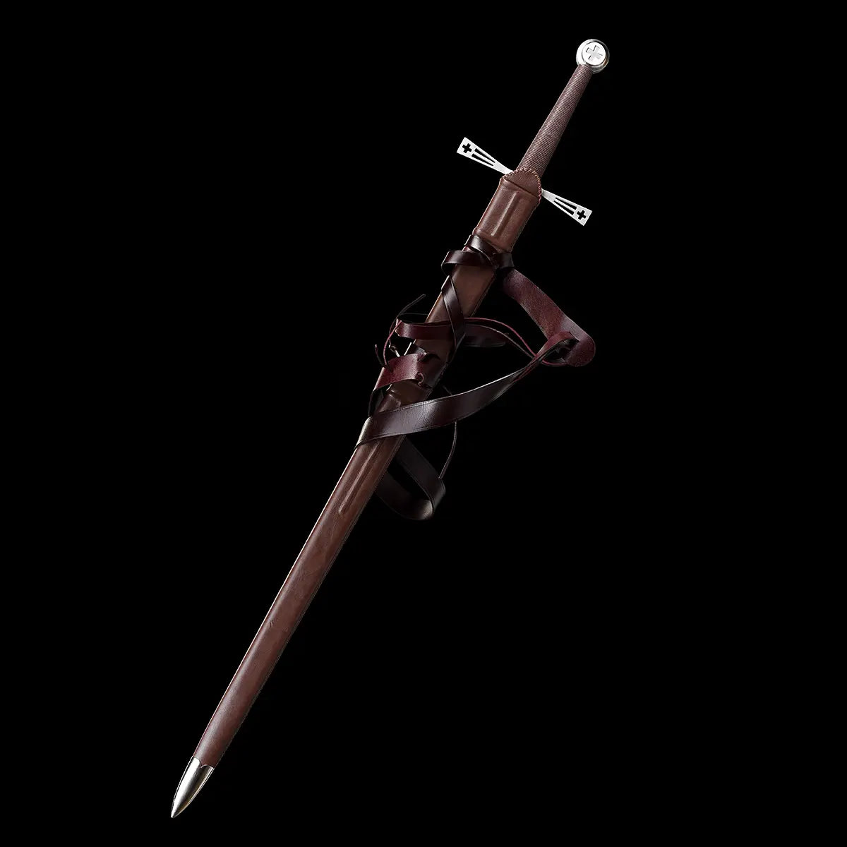 Épée longue médiévale Crux Bellator rangée dans son fourreau en cuir brun, sangles d’attache en cuir enroulées autour du fourreau, garde en croix ajourée en acier brillant, pommeau rond métallique, le tout présenté sur fond noir uniforme pour mettre en valeur les matières, la silhouette et les détails de la longsword.