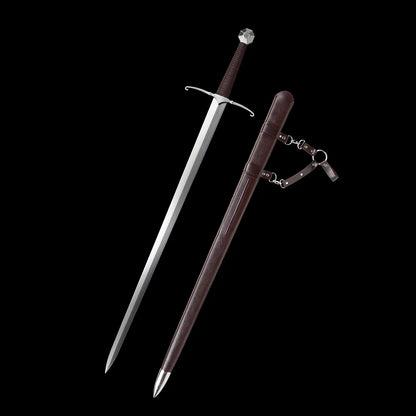 Épée longue médiévale Castelar présentée avec la lame dégagée à côté de son fourreau en bois gainé de simili cuir brun, sur fond noir uniforme. Lame droite en acier 1060 polie miroir, quillons en croix argentés légèrement courbés, poignée brun foncé et pommeau évasé facetté. Fourreau brun doté d’attaches métalliques et de lanières en cuir synthétique. Image détaillée idéale pour les recherches épée longue médiévale, longsword main-et-demi, acier 1060, épée de coupe ou décoration.
