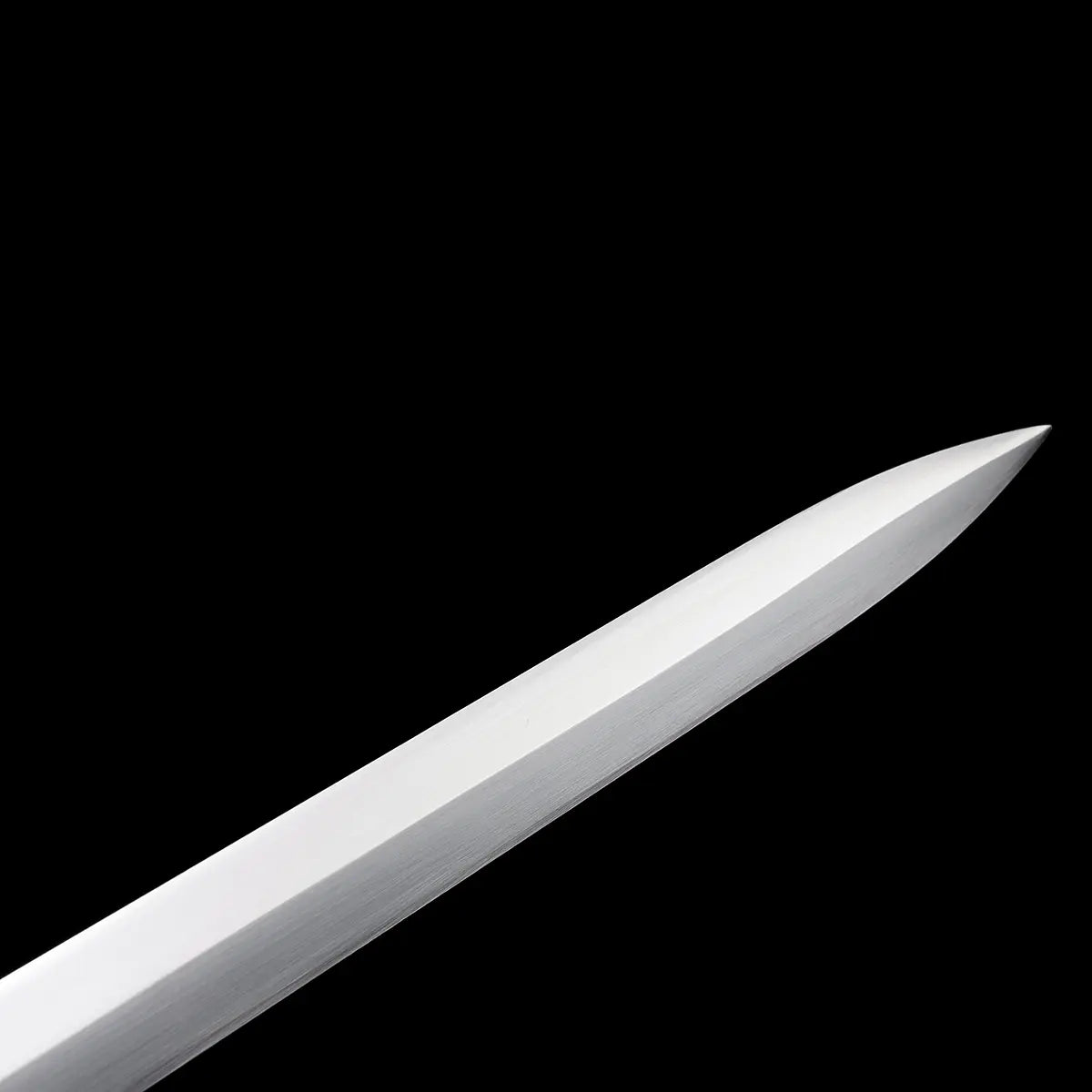Gros plan sur la pointe de l’épée longue médiévale Castelar, lame droite en acier 1060 polie avec biseau net, photographiée sur fond noir uniforme. L’image met en valeur la finesse de l’affûtage, la géométrie de la pointe et la surface satinée de l’acier. Parfaite pour les recherches liées à épée longue médiévale, détail lame, pointe acier 1060, longsword affûté.