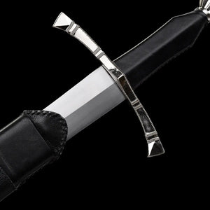 Gros plan sur la zone de sortie de lame de l’épée longue médiévale Corvus, lame droite en acier carbone 1060 finition satinée émergeant du fourreau en cuir noir, garde en croix à quillons droits en métal poli protégeant la main, poignée gainée de cuir sombre, photographiée sur fond noir profond pour une ambiance martiale, sobre et authentique.