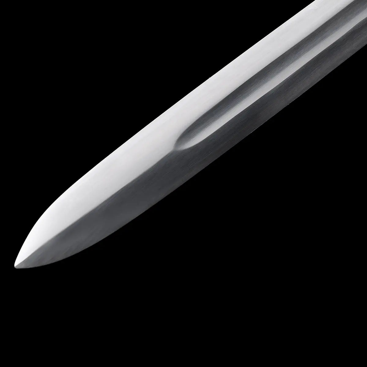 Gros plan sur la pointe de la lame de l’épée longue médiévale Ravenna, photographiée en diagonale sur fond noir profond. Pointe effilée en acier 1060 avec profil régulier et polissage satiné, conçue pour un bon compromis coupe et estoc. Finition sobre et fonctionnelle, adaptée à la pratique AMHE / HEMA, à l’entraînement contrôlé ou à la collection médiévale.