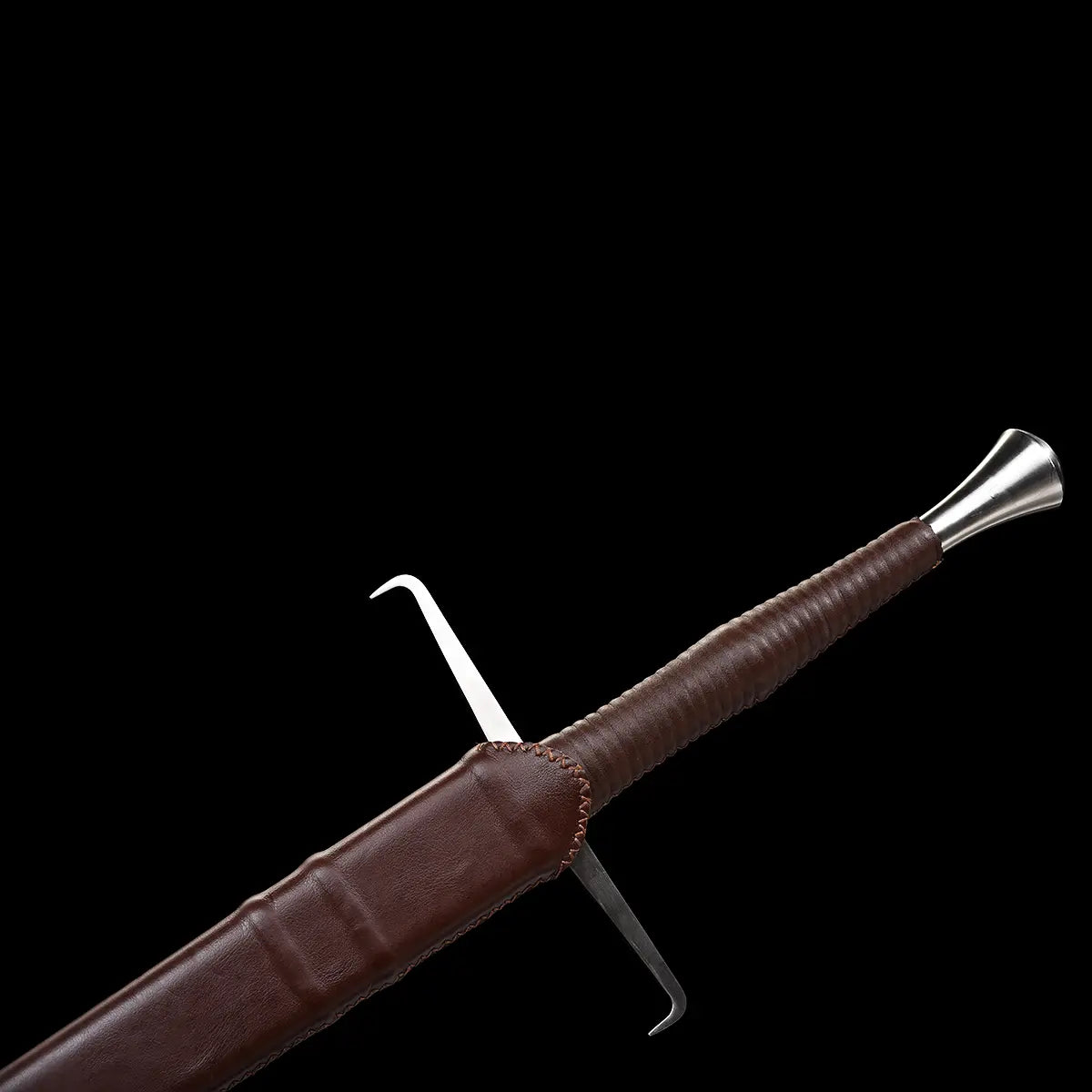 Détail de l’épée longue médiévale Vesper partiellement rangée dans son fourreau en cuir brun, montrant la garde en croix droite, la poignée gainée de cuir brun et le pommeau évasé en acier, avec couture visible sur le fourreau ; le tout présenté sur un fond noir qui met en valeur les textures du cuir et du métal — épée longue médiévale 1060, longsword main-et-demi, fourreau cuir brun.
