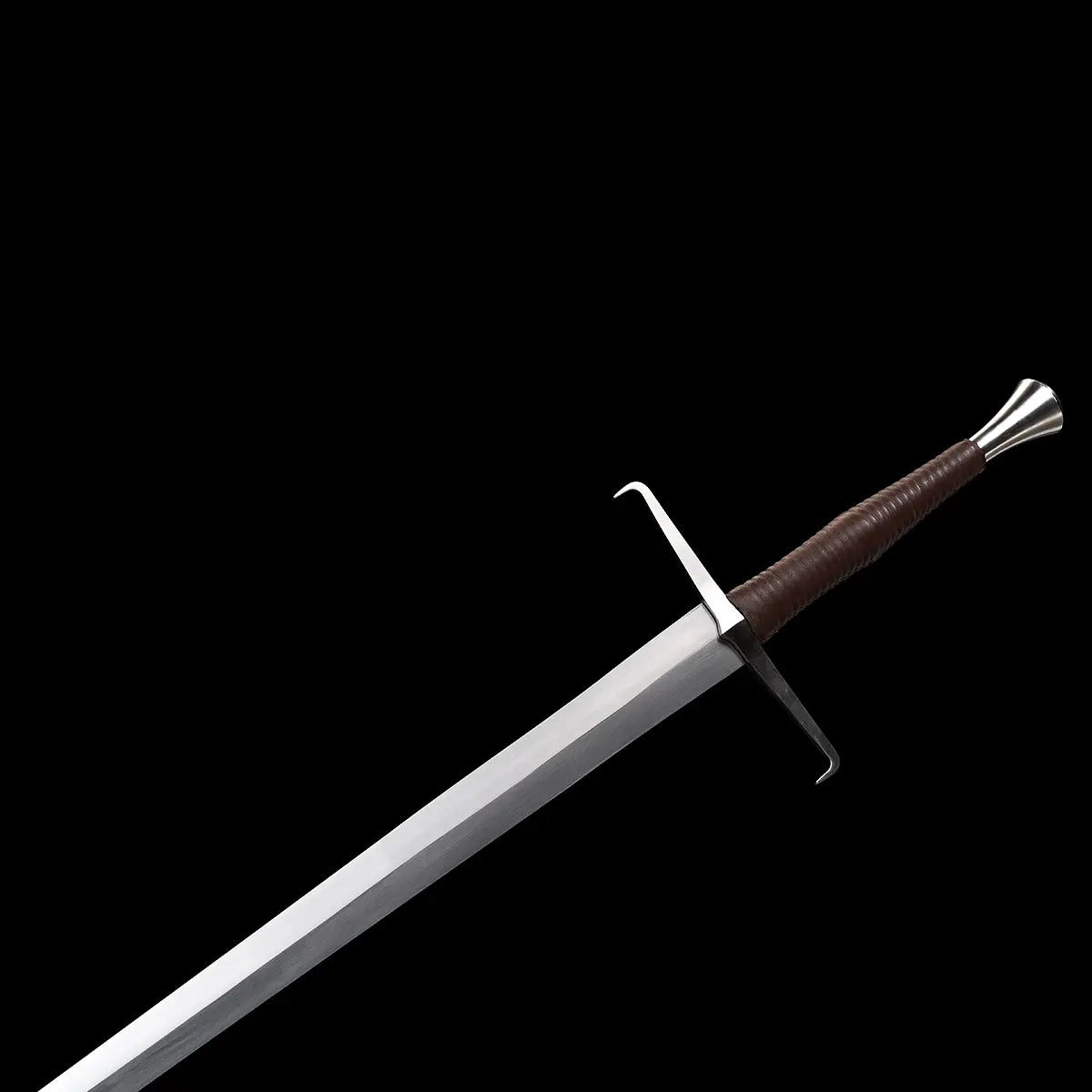 Vue détaillée de l’épée longue médiévale Vesper montrant la lame en acier 1060 polie, la garde en croix aux quillons droits et la poignée gainée de cuir brun se terminant par un pommeau évasé en acier, le tout présenté sur un fond noir pour souligner les contrastes et la géométrie du longsword — épée médiévale 1060, main-et-demi, finition premium.