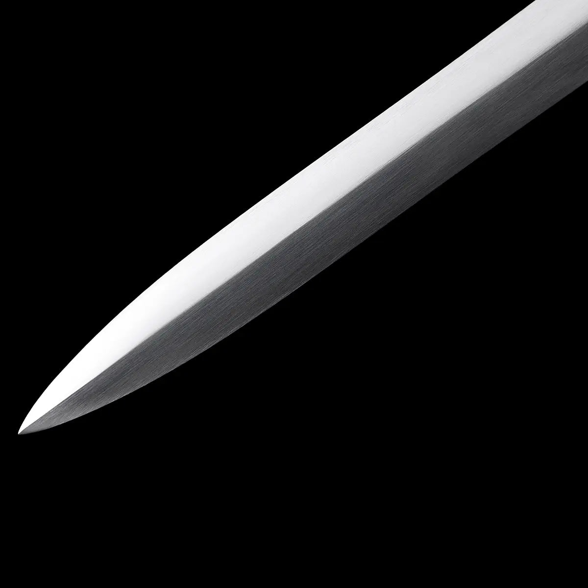 Gros plan de la pointe de l’épée longue médiévale Vesper, lame en acier 1060 polie avec reflets métalliques, montrée sur fond noir uniforme pour mettre en valeur le tranchant, la ligne de coupe et la finition satinée — épée longue, longsword main-et-demi, acier 1060.