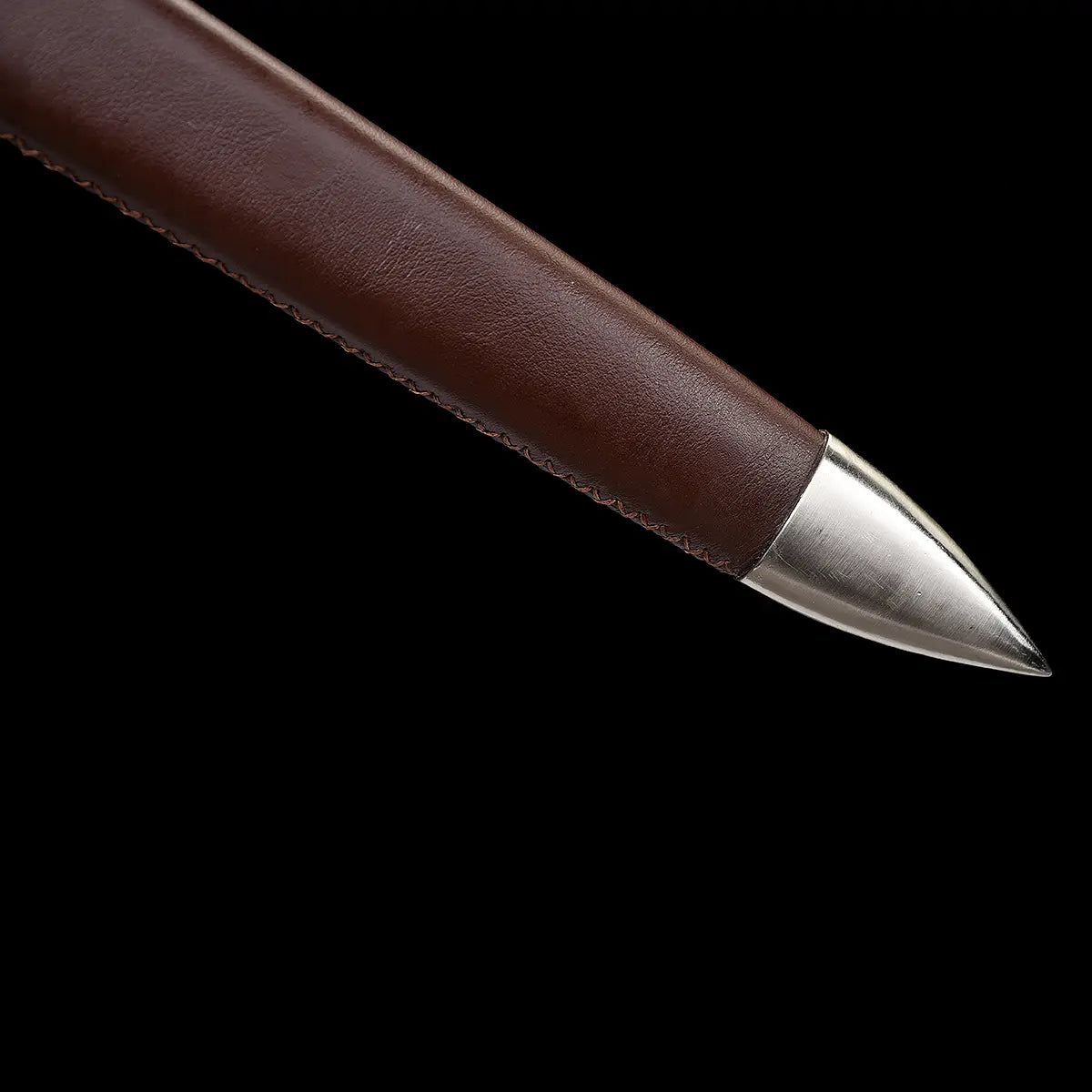 Gros plan du pommeau évasé type poire et de l’extrémité du fourreau en cuir brun, finition métal poli, épée longue médiévale Valmont en acier 1060, fond noir studio, style sobre et authentique, inspiration européenne médiévale