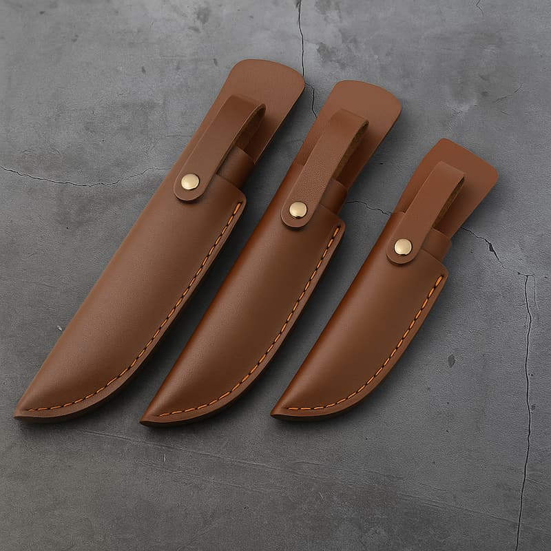 Trois étuis en cuir Punisher marron vus de dos, couture orange, avec passant ceinture, posés sur un fond béton gris texturé.