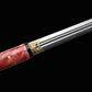 Épée chinoise Jian FEN LIN avec lame droite double tranchant partiellement sortie du fourreau rose en peau de raie, gros plan sur la garniture dorée gravée, finition noire du fourreau et surface métallique polie sur fond noir.