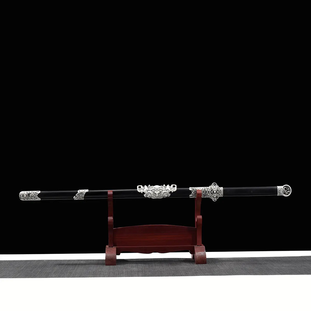 Épée chinoise Jian FENG YIN présentée sur un support en bois rouge avec fond noir. Jian chinois traditionnel avec fourreau noir laqué, garnitures métalliques argentées gravées, poignée travaillée et pommeau décoratif. Vue latérale complète mettant en valeur une épée chinoise droite artisanale destinée à la collection, au Tai Chi, au Wushu et aux arts martiaux chinois.