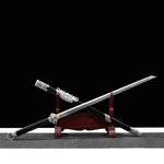 Épée chinoise Jian FENG YIN partiellement sortie de son fourreau noir, présentée en diagonale sur un support en bois rouge avec fond noir. La lame droite gravée, la garde argentée travaillée, le pommeau décoratif et les garnitures métalliques du fourreau mettent en valeur un Jian chinois artisanal de collection, adapté au Tai Chi, au Wushu et à la décoration.