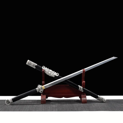 Épée chinoise Jian FENG YIN partiellement sortie de son fourreau noir, présentée en diagonale sur un support en bois rouge avec fond noir. La lame droite gravée, la garde argentée travaillée, le pommeau décoratif et les garnitures métalliques du fourreau mettent en valeur un Jian chinois artisanal de collection, adapté au Tai Chi, au Wushu et à la décoration.