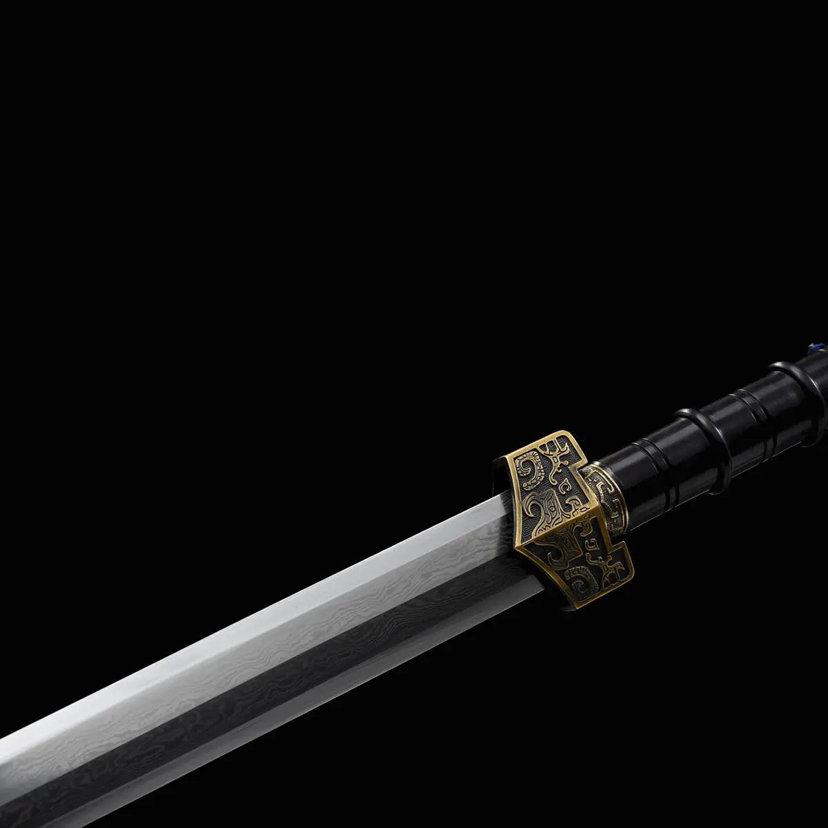 Gros plan sur l’épée chinoise Jian HAN YUN, avec lame droite en acier plié, garde métallique dorée gravée, poignée noire sculptée et contraste marqué sur fond noir.