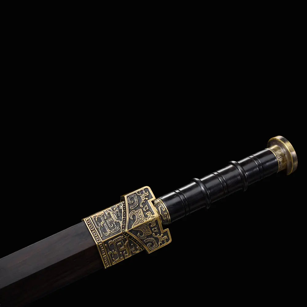 Gros plan sur la poignée noire de l’épée chinoise Jian HAN YUN, avec fourreau en ébène sombre, garde gravée, pommeau métallique doré vieilli et ornements décoratifs sur fond noir.
