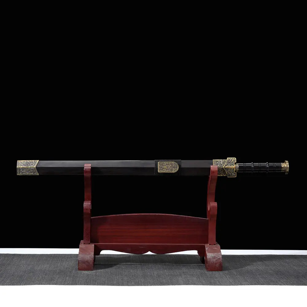 Épée chinoise Jian HAN YUN rangée dans son fourreau en ébène, présentée horizontalement sur support en bois rouge, avec poignée noire, pommeau doré vieilli et garnitures métalliques gravées sur fond noir.