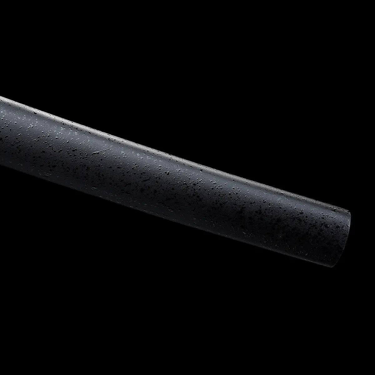 Gros plan sur l’extrémité du fourreau saya du katana japonais artisanal Kazekiri, saya en bois dur avec finition laquée noire mate à texture granuleuse visible, surface légèrement irrégulière mettant en valeur le travail artisanal, fond noir uniforme soulignant la sobriété et l’esthétique minimaliste du fourreau
