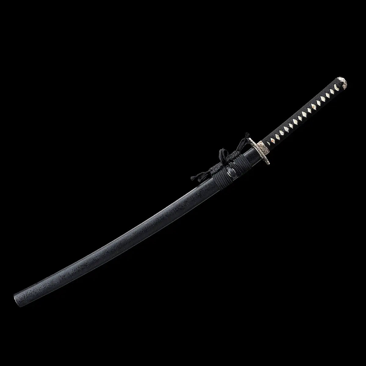 Vue complète du katana japonais artisanal Kazekiri entièrement dans son fourreau, posé en diagonale sur fond noir uniforme, saya noir texturé avec finition mate et cordage sageo noir noué près de la bouche, manche tsuka visible avec tressage ito noir et losanges de samegawa claire, garde tsuba en métal sculpté aux motifs ondulés, absence de support visible, composition épurée mettant en valeur les lignes et l’équilibre général de l’arme
