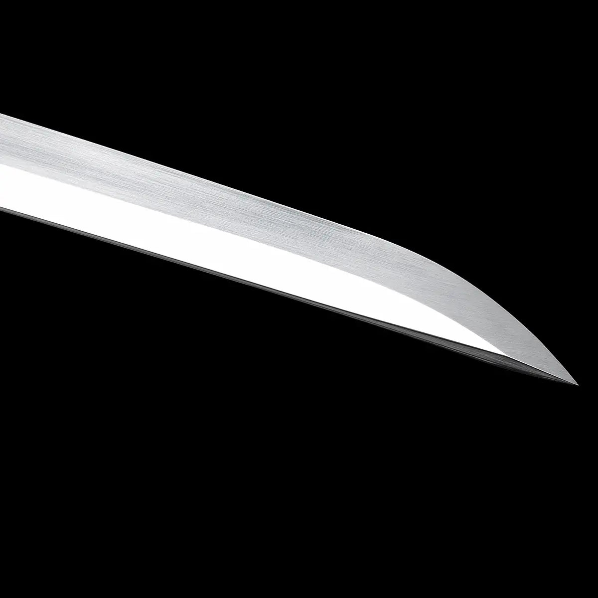 Gros plan sur la pointe de la lame du katana japonais artisanal Kazekiri, lame en acier carbone 1060 avec géométrie unokubi-zukuri, tranchant poli brillant contrastant avec le dos satiné, courbure marquée de la pointe kissaki, texture de l’acier visible, fond noir uniforme mettant en valeur la ligne de coupe
