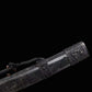 Gros plan du fourreau noir du sabre chinois Dao KANGXI LONG, avec texture mouchetée, garnitures métalliques sombres gravées, motif de dragon visible, cordon noir et perles décoratives sur fond noir.