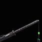 Gros plan de la poignée noire du sabre chinois Dao KANGXI LONG, avec garde ronde, garnitures gravées, cordon décoratif, perles vertes et extrémité du fourreau noir moucheté sur fond noir.