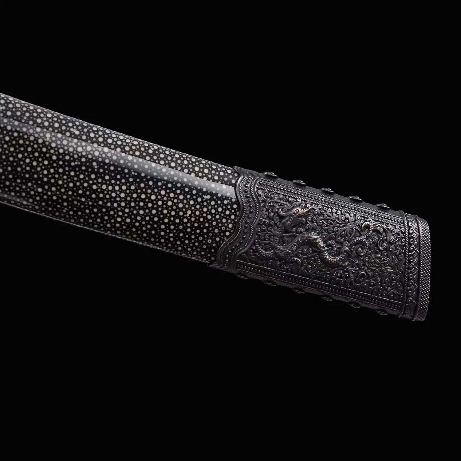 Gros plan du fourreau noir moucheté du sabre chinois Dao KANGXI LONG, avec extrémité métallique sombre gravée, motif de dragon visible, texture brillante et finition décorative sur fond noir.