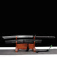 Sabre chinois Dao KANGXI LONG exposé hors du fourreau sur un support en bois, avec lame courbe argentée à double gorge, poignée noire texturée, garde ronde et fourreau noir gravé sur fond noir.