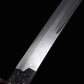 Gros plan de la lame courbe du sabre chinois Dao KANGXI LONG, avec acier plié aux motifs visibles, double gorge d’allègement, base noire gravée et finition métallique sur fond noir.