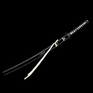 Katana de Beatrix Kiddo dans Kill Bill, réplique collector avec saya noir laqué décoré d’emblèmes dorés, tsuka noir et blanc, sageo blanc, présenté sur fond noir minimaliste.