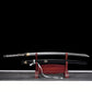 Katana de Bill dans Kill Bill présenté complet sur un support en bois rouge, lame en acier carbone 1045 hamon ondulé, saya noir laqué avec ornements dorés et manche tsuka noir tressé, fond noir minimaliste.