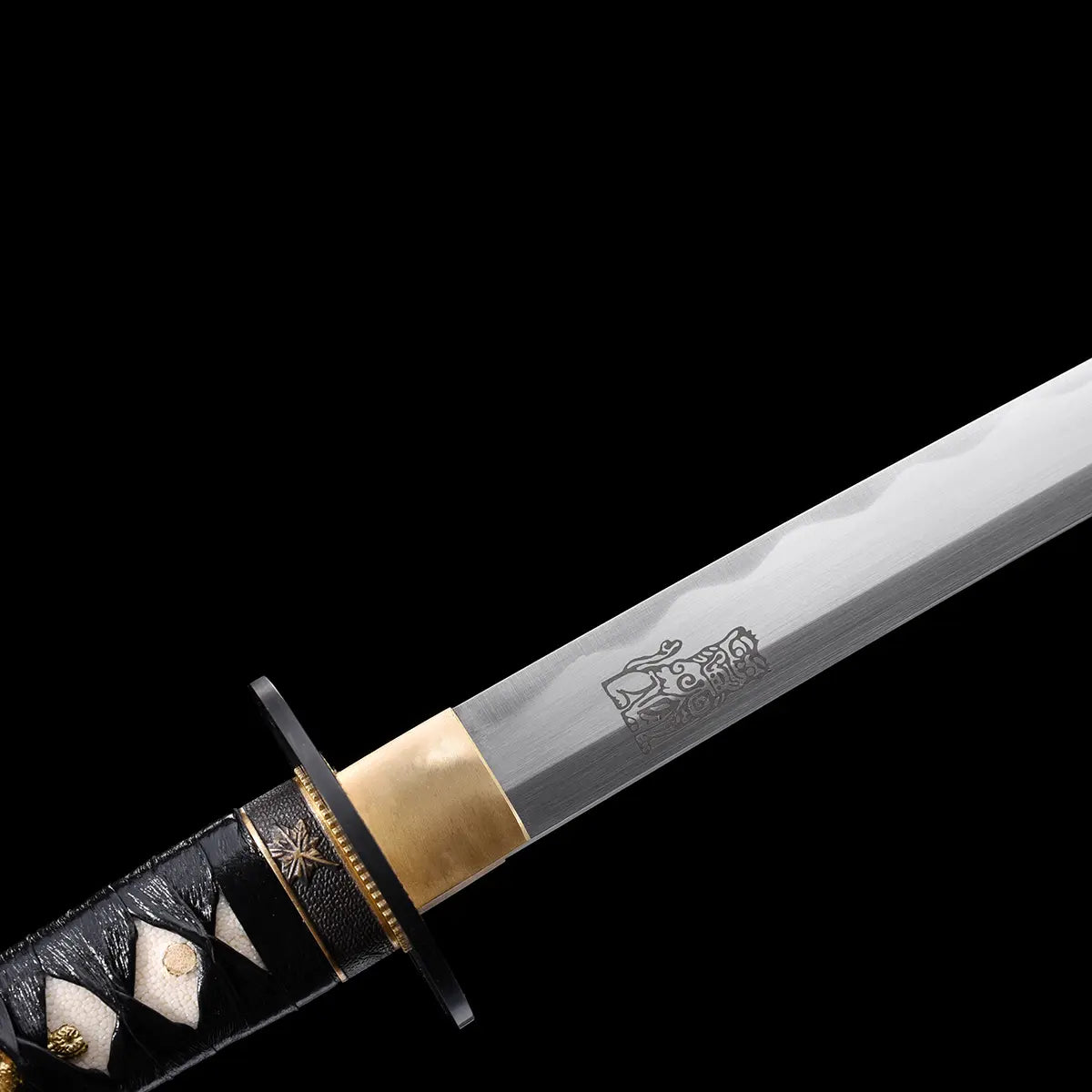 Détail du Katana de la Mariée dans Kill Bill, lame en acier carbone 1045 polie avec gravure décorative, habaki doré et tsuka noir en cuir avec motifs samegawa blanc et ornements dorés, sur fond noir.