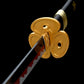 Gros plan sur la finition dorée et la lame rouge du katana japonais Enma Black, sabre collector inspiré de One Piece.