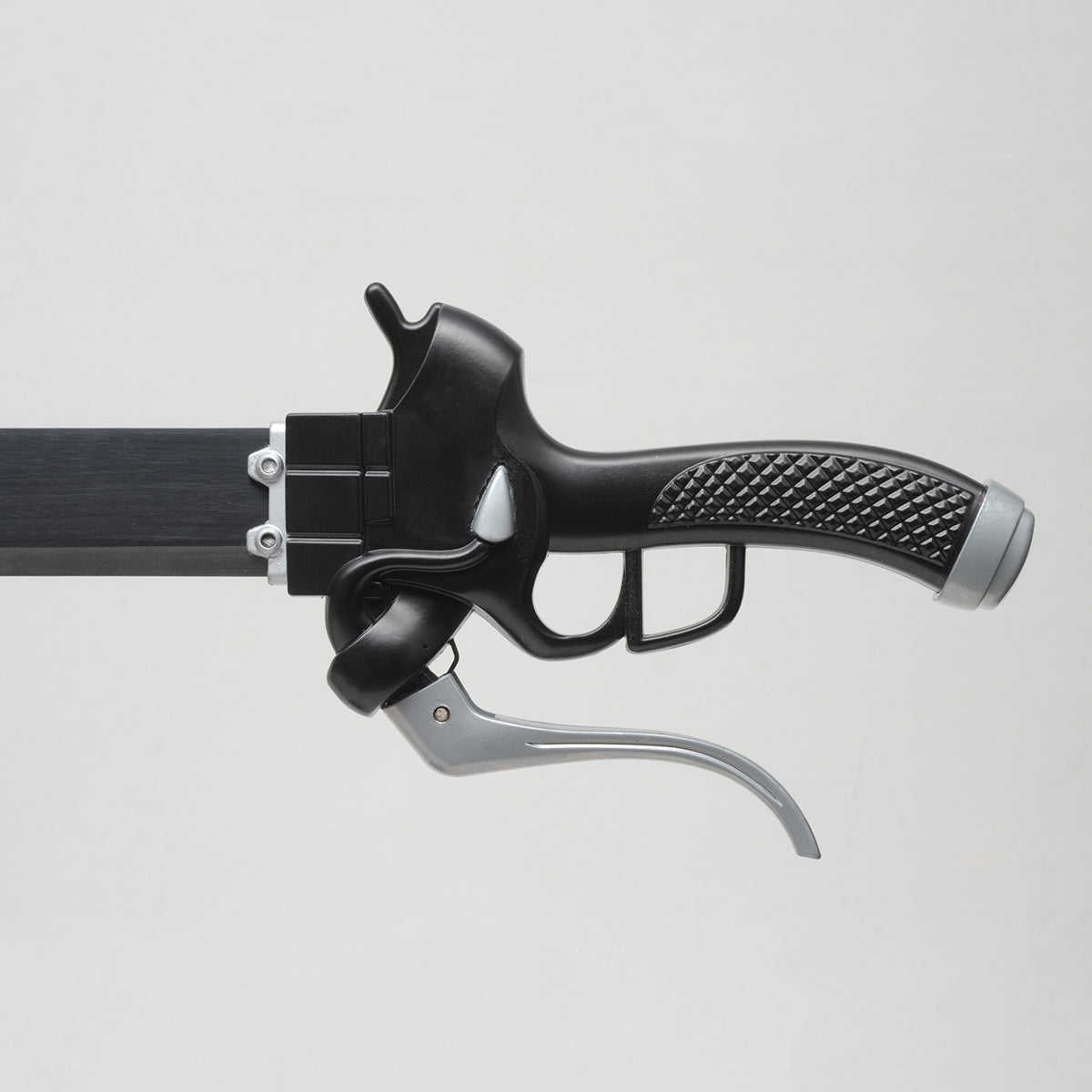 Vue rapprochée de la poignée du katana de Eren Jäger “Lame anti-Titans”, réplique Attack on Titan, manche noir texturé avec détails argentés et levier métallique, photographié sur fond gris clair minimaliste.