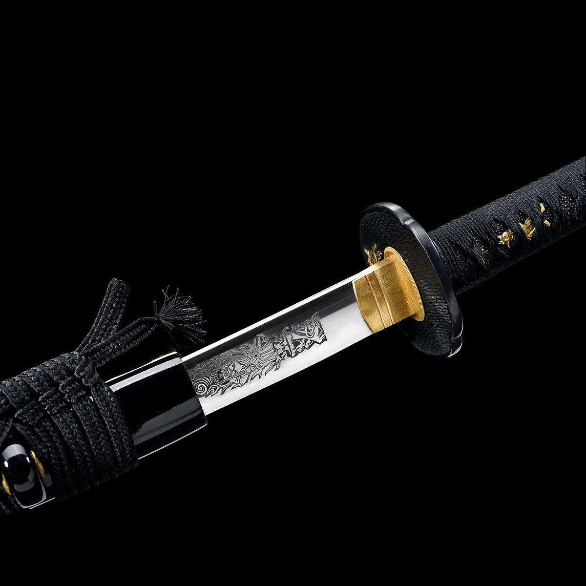 Japanese katana shown partially unsheathed against a deep black background, polished steel blade emerging from a glossy black lacquered wooden scabbard, engraved Fudo Myoo figure visible near the base of the blade, gold-colored brass habaki fitted tightly at the guard, round black textured tsuba, black handle wrapped with black cord over ray skin, braided black sageo tied around the saya, focus on blade engraving, fittings, and traditional materials.
