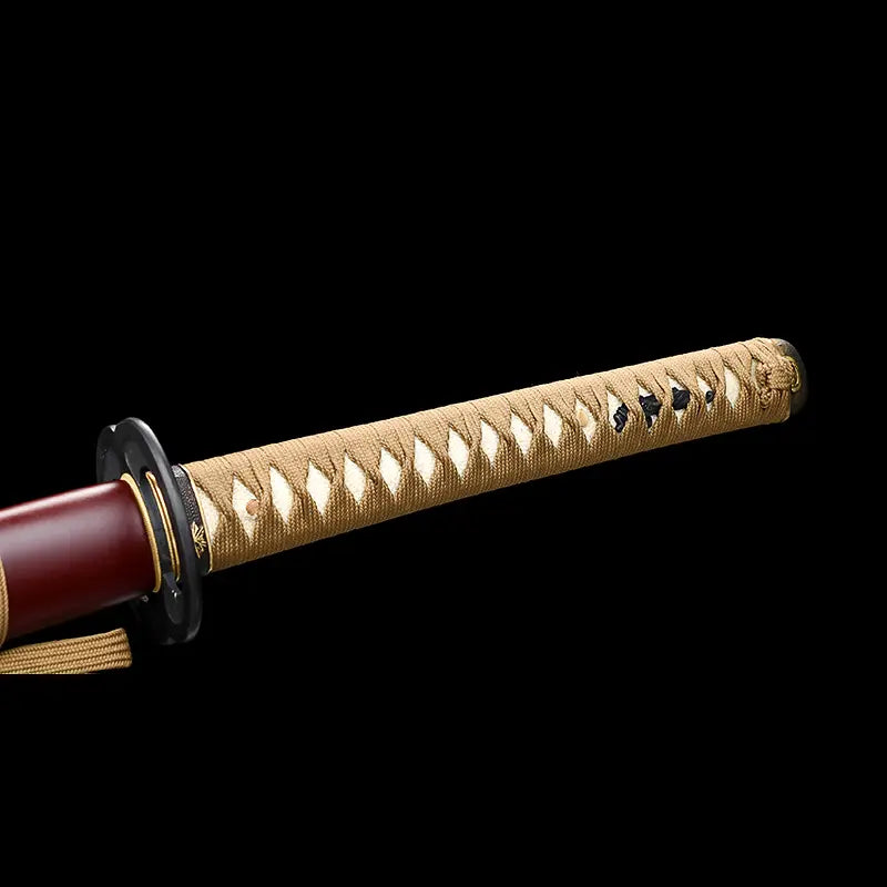 Detail du manche tsuka du katana Himura Kenshin Sakabato sur fond noir, poignee beige tresse laissant apparaitre la peau de raie blanche, garde noire ronde et fourreau rouge laque partiellement visible.
