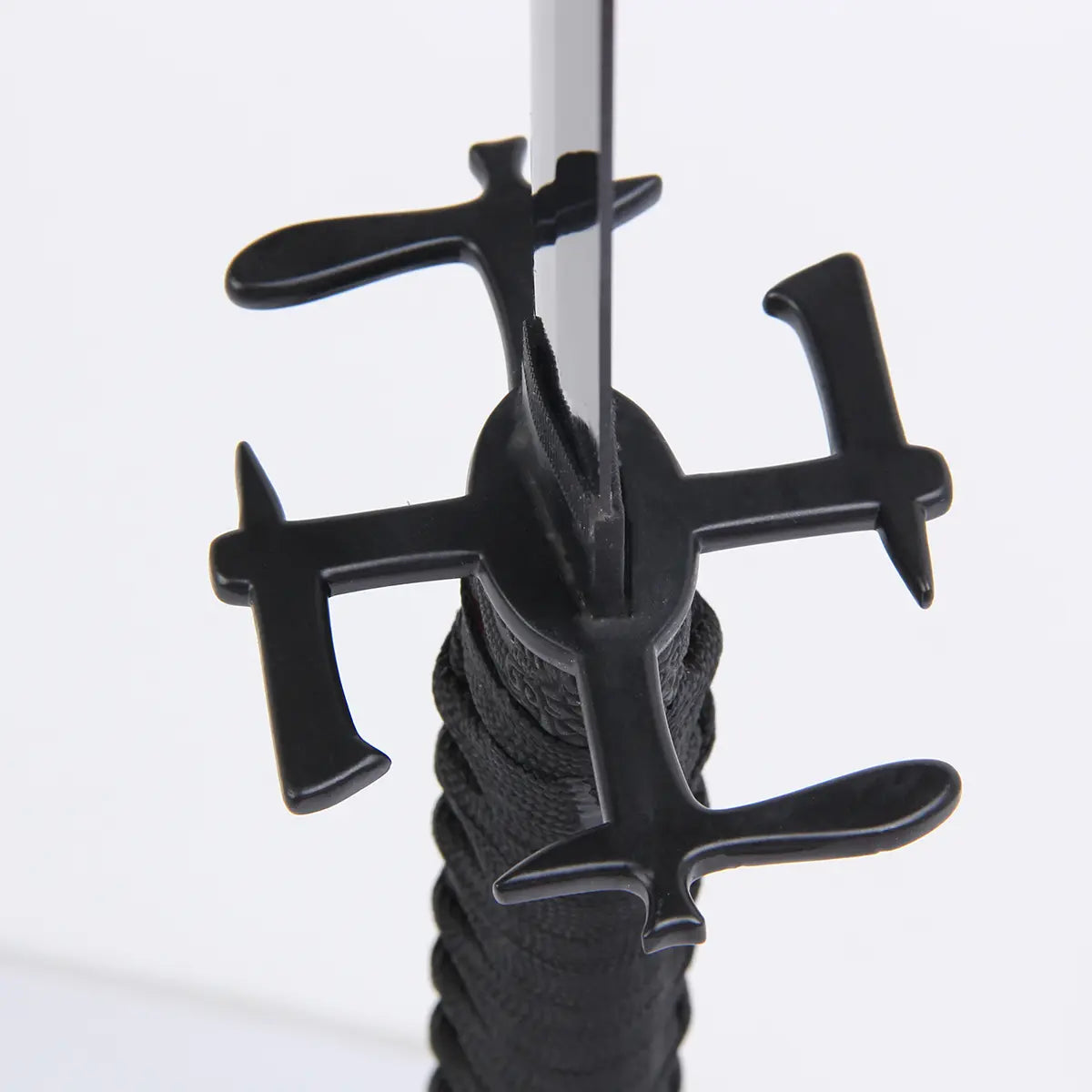 Gros plan de la garde noire en croix (tsuba) du katana Ichigo Kurosaki Tensa Zangetsu de Bleach, lame dressée et tsuka en tressage noir, fond blanc neutre.