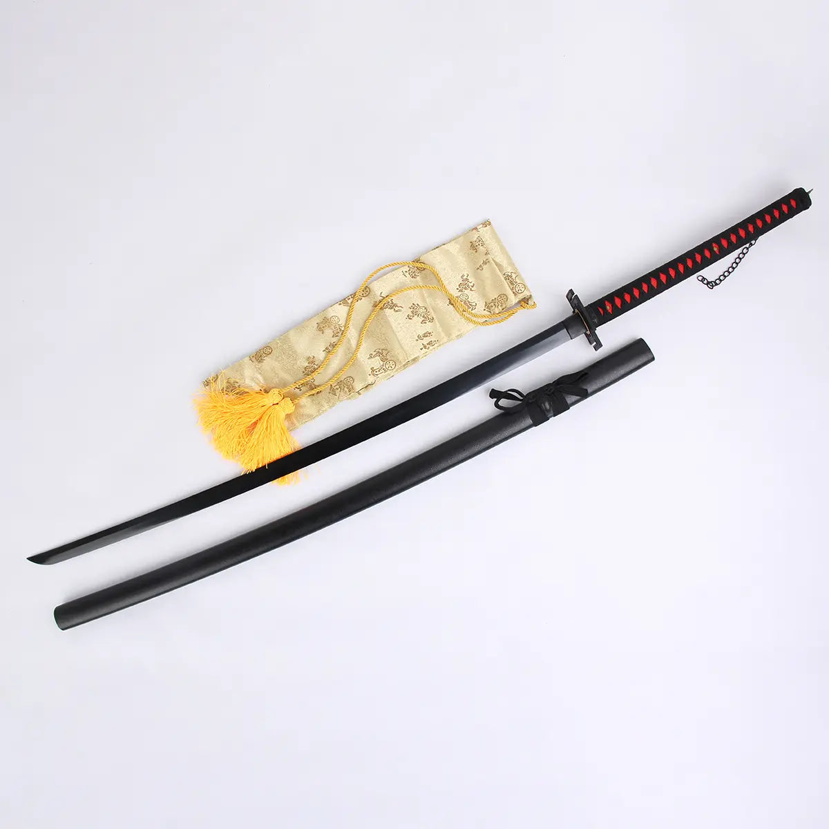 Réplique du katana Ichigo Kurosaki Tensa Zangetsu version classique, inspiré du Bankai de Bleach, lame en acier carbone 1045, avec fourreau noir mat, poignée noire tressée à losanges rouges, chaînette décorative et housse dorée posés sur fond blanc.