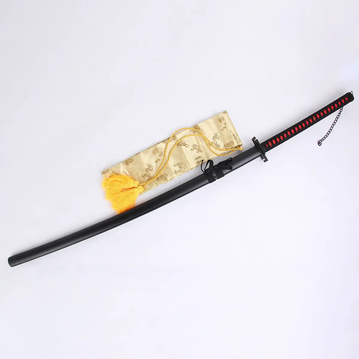 Photo du katana Ichigo Kurosaki Tensa Zangetsu version classique, réplique Bankai de Bleach en acier carbone 1045, avec fourreau noir mat, poignée noire et losanges rouges, posé sur un fond blanc avec une housse décorative dorée.