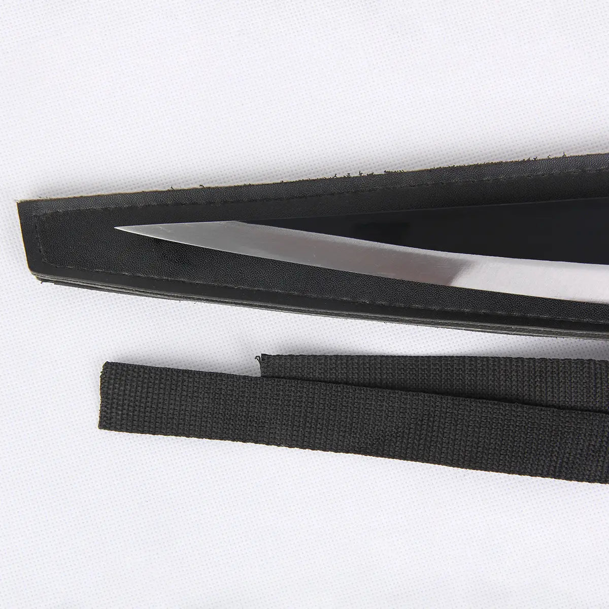 Détail de la lame argentée du katana Ichigo Zangetsu Shikai de Bleach partiellement insérée dans son fourreau noir, avec sangle en tissu noir visible, posé sur un fond blanc neutre. Réplique idéale pour cosplay, décoration et collection.