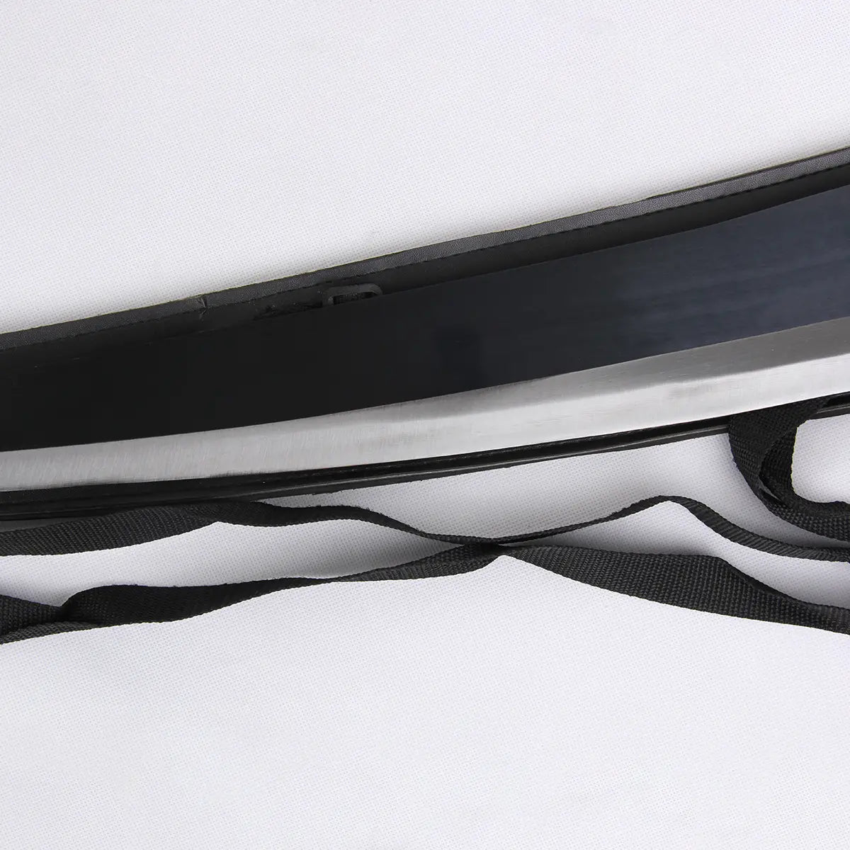Vue rapprochée de la lame noire et tranchant argenté du katana Ichigo Zangetsu Shikai de Bleach, posé dans son fourreau noir avec sangle en tissu, présentée sur fond blanc. Réplique fidèle idéale pour cosplay, décoration et collection.
