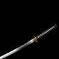 Katana japonais artisanal Ryū no Kiba présenté sans fourreau sur fond noir uni, lame partiellement visible avec horimono représentant un dragon gravé dans l’acier, hamon ondulé discret le long du tranchant, poignée tsuka noire tressée avec losanges blancs en peau de raie, habaki doré et garde tsuba ronde en métal patiné, aucun support apparent.
