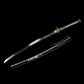 Katana japonais artisanal Ryū no Kiba présenté sur fond noir uni avec la lame dégainée et le fourreau disposé séparément, lame courbe en acier poli montrant un hamon ondulé discret, horimono de dragon gravé visible sur la lame, poignée tsuka noire tressée avec losanges blancs en peau de raie, garde tsuba ronde en métal patiné et habaki doré, saya noir laqué avec sageo noir noué, ensemble sans support apparent.
