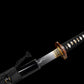 Katana japonais artisanal Ryū no Kiba partiellement dégainé sur fond noir uni, lame sortant du saya noir laqué révélant un horimono discret près du habaki doré, hamon ondulé visible dans l’acier poli, poignée tsuka noire tressée avec losanges blancs en peau de raie, garde tsuba ronde en métal patiné, aucun support apparent.
